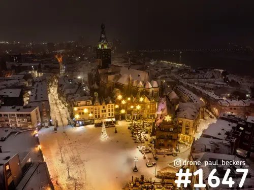 Luchtfoto van de Grote Markt in Nijmegen in de sneeuw 's avonds, met de Stevenskerk, kerstboom en verlichte gevels