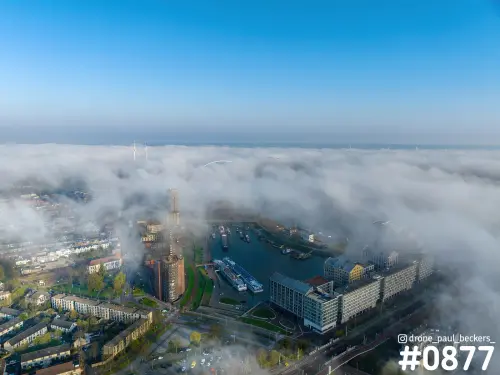 Luchtfoto van de Handelskade en het Havenkwartier in Nijmegen, met een laag mist rond de jachthaven en een blauwe lucht erboven