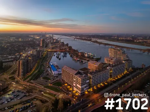 Luchtfoto van de Handelskade en het Havenkwartier in Nijmegen bij zonsondergang, met de Waal en De Oversteek in de verte