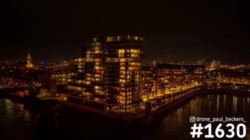 Nachtelijke luchtfoto van een verlicht appartementencomplex aan de Handelskade in Nijmegen, met de Stevenskerk links