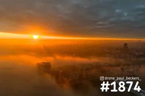 Zonsopkomst boven de Handelskade in Nijmegen, mist rond het gebouw Nimbus en de toren van de Stevenskerk in de verte