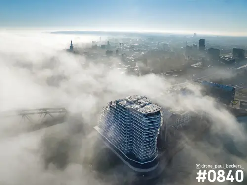Luchtfoto van woontoren Nimbus aan de Handelskade in Nijmegen met mist boven de Waal en de Stevenskerk op de achtergrond