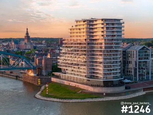 Luchtfoto van de hoogbouw aan De Handelskade in Nijmegen bij laagstaande zon, met de Stevenskerk op de achtergrond