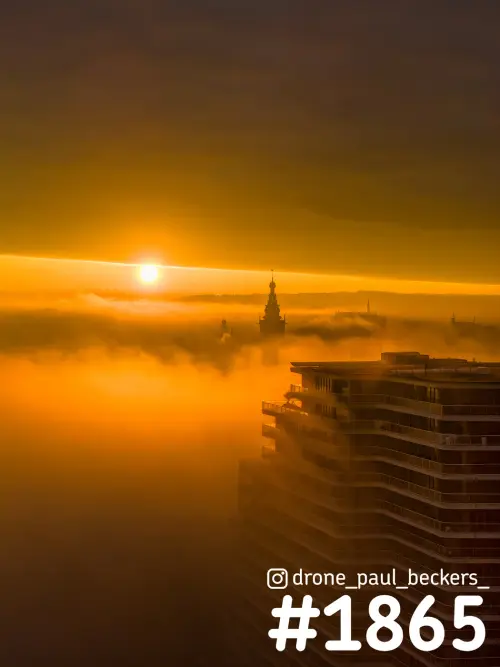 Luchtfoto van de Handelskade in Nijmegen bij zonsopkomst, met de toren van de Stevenskerk boven de oranje mist