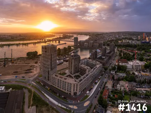 Luchtfoto van woontorens aan de Handelskade in Nijmegen met laagstaande zon boven de Waal en de Waalbrug in de verte