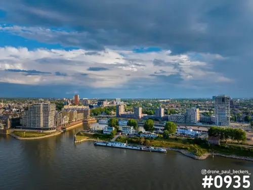 Luchtfoto van de Waal bij de Handelskade in Nijmegen met woontorens aan de kade en een dreigende wolkenlucht erboven