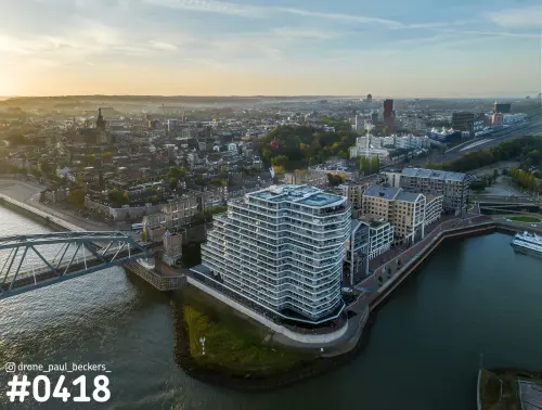 Luchtfoto van de Handelskade in Nijmegen met het golvende appartementengebouw aan de Waal, bij zonsopkomst
