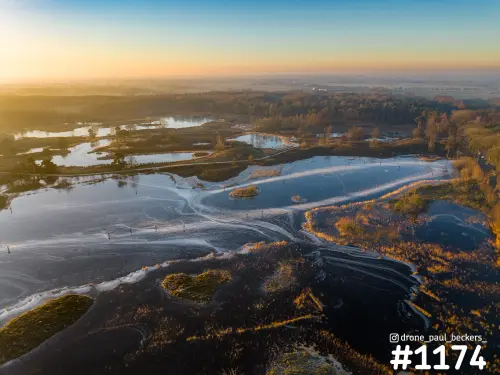Luchtfoto van de Hatertse Vennen met deels bevroren water, rietkragen en bos in laagstaand zonlicht