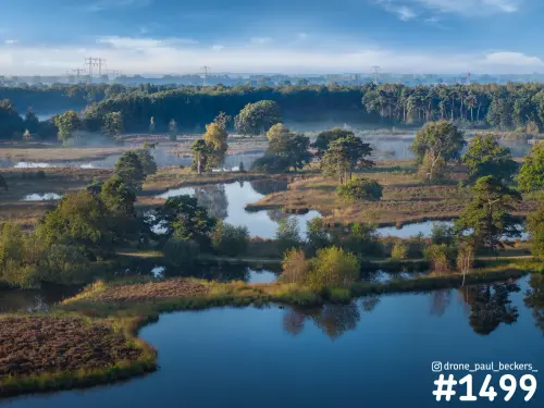 Luchtfoto van de Hatertse Vennen bij Nijmegen met vennen, heide en bomen in ochtendlicht en lichte mist in de verte