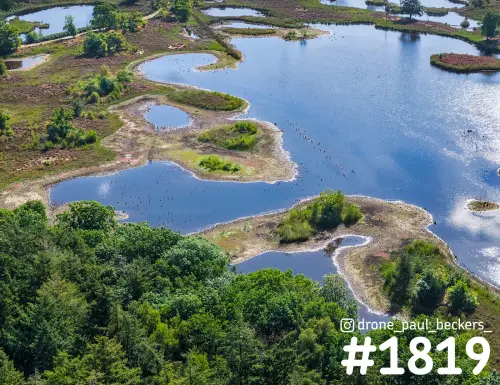 Luchtfoto van de Hatertse Vennen bij Nijmegen met eilandjes in het zonnige water en bos op de voorgrond