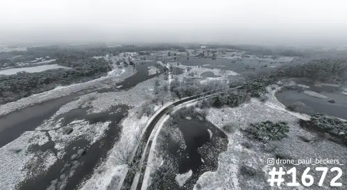 Luchtfoto van de Hatertse Vennen bij Nijmegen onder een laagje sneeuw, met donkere vennen en een smal pad in de mist