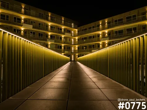 Verlicht looppad in het Havenkwartier bij nacht, met gele ledverlichting langs het hekwerk en appartementen met balkons