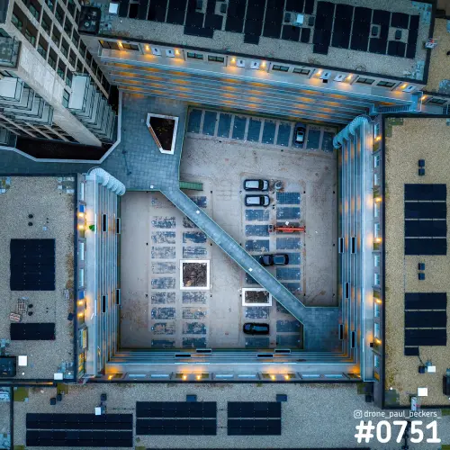 Luchtfoto recht van boven op een binnenplaats in het Havenkwartier in Nijmegen, met een diagonaal pad, auto's en zonnepanelen op daken