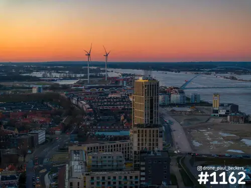 Luchtfoto van het Havenkwartier in Nijmegen bij zonsondergang, met woontoren, windmolens en De Oversteek over de Waal
