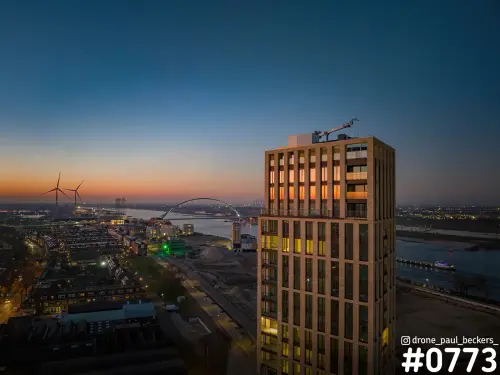 Luchtfoto van het Havenkwartier in Nijmegen bij schemering, met hoge toren op de voorgrond en De Oversteek over de Waal