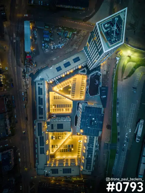 Luchtfoto recht van boven van een woontoren en verlicht appartementencomplex in het Havenkwartier in Nijmegen in de avondschemering