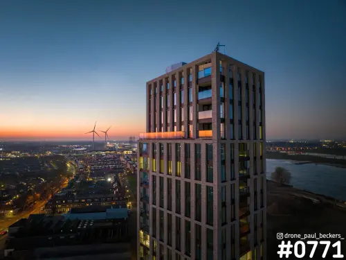 Luchtfoto van woontoren met bakstenen gevel in het Havenkwartier in Nijmegen, in de avondschemering aan de Waal