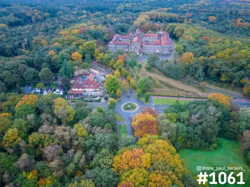 Luchtfoto van Heilig Landstichting bij Nijmegen in herfstkleuren, met het kloostergebouw en een rotonde tussen bos