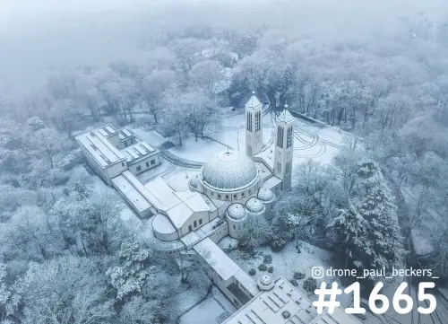 Luchtfoto van de koepelkerk in Heilig Landstichting bij Nijmegen, met sneeuw op de daken en berijpte bomen in de mist