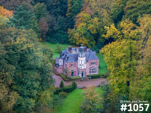 Luchtfoto van een landhuis met toren en rood-wit gestreepte luiken tussen herfstbomen in Heilig Landstichting bij Nijmegen