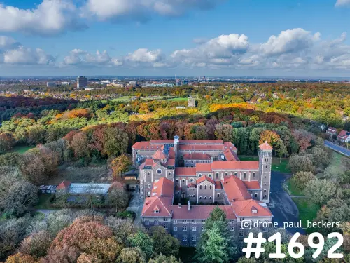 Luchtfoto van Heilig Landstichting bij Nijmegen met rode daken en toren, omringd door herfstbos in geel en oranje