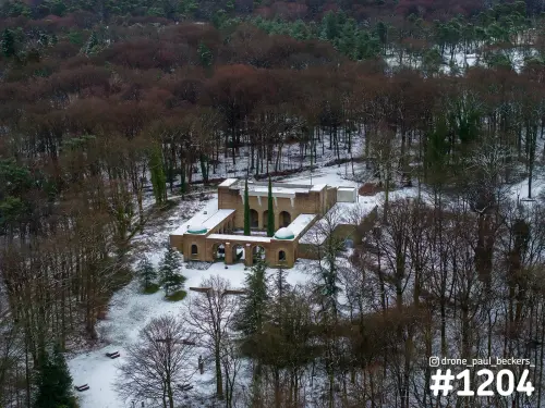 Luchtfoto van het bakstenen gebouw met arcade in Heilig Landstichting bij Nijmegen, omringd door kale bomen en sneeuw