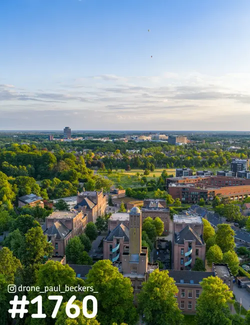 Luchtfoto van Heyendaal in Nijmegen-Oost met bakstenen universiteitsgebouwen, een toren en veel groen bij zacht avondlicht
