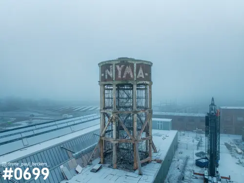 Luchtfoto van de NYMA-toren op het Haven- en Industrieterrein Nijmegen in mist, met sneeuw op de daken