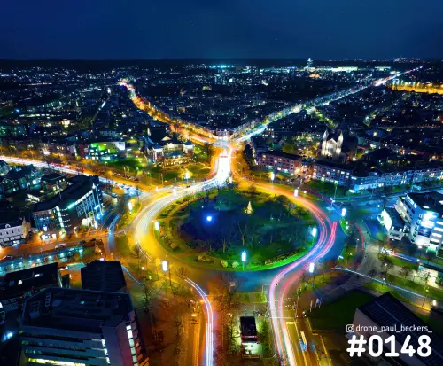 Luchtfoto van Keizer Karel Plein in Nijmegen 's avonds, met lichtsporen van verkeer rond de rotonde en verlichte straten
