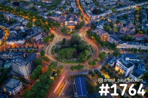 Luchtfoto van Keizer Karel Plein in Nijmegen in de schemering, met lichtsporen van verkeer rond de groene rotonde
