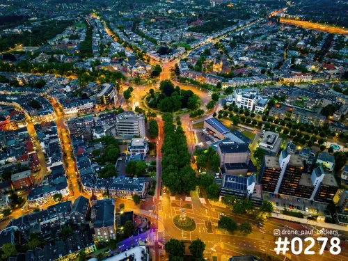 Luchtfoto van Keizer Karel Plein in Nijmegen in de avondschemering, met oranje verlichte straten en een bomenlaan