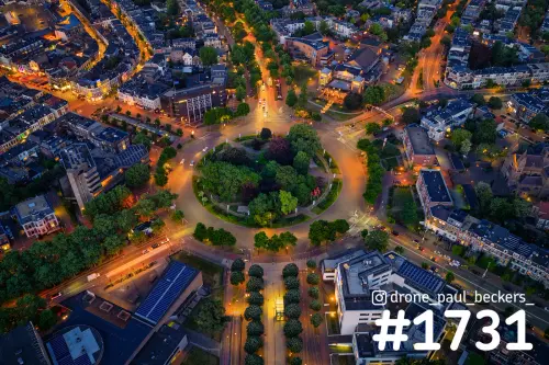 Luchtfoto van het Keizer Karel Plein in Nijmegen in de avondschemering, met verlichte rotonde en groen in het midden