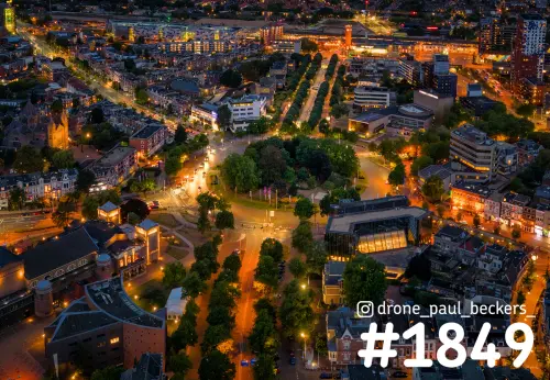 Luchtfoto van het Keizer Karel Plein in Nijmegen in de avond, met verlichte bomenlanen richting het stationsgebied