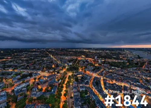 Luchtfoto van Nijmegen bij Keizer Karel Plein in de avondschemering, oranje straatlicht onder donkere wolken