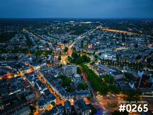 Luchtfoto van Keizer Karel Plein in Nijmegen in de blauwe schemering, met verlichte straten en bomen rond het plein