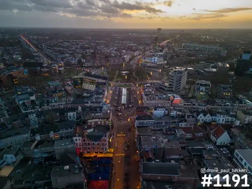 Luchtfoto van het centrum van Nijmegen bij Keizer Karel Plein in de schemering, met verlichte straat en gekleurde kramen