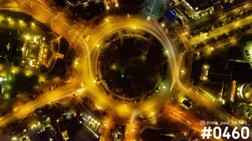 Luchtfoto van Keizer Karel Plein in Nijmegen bij nacht, recht van boven met gouden lichtsporen rond het middenplein