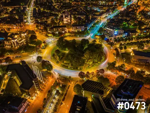 Luchtfoto van het Keizer Karel Plein in Nijmegen bij nacht, met lichtsporen van verkeer rond de groene rotonde