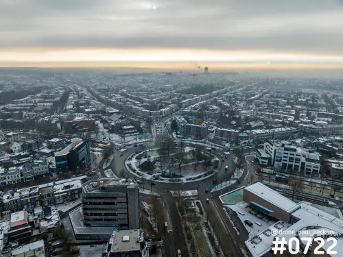 Luchtfoto van het Keizer Karel Plein in Nijmegen met sneeuw op het rondweg-plein en een oranje horizonlijn boven de wijken
