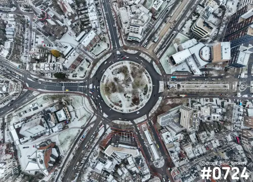 Luchtfoto recht van boven op het Keizer Karel Plein in Nijmegen met sneeuw op het rond park en daken rondom de rotonde