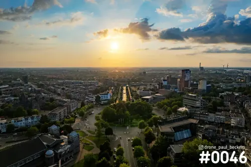Luchtfoto van Keizer Karel Plein in Nijmegen bij laagstaande zon, met wolken boven woonwijken en een lange laan met bomen