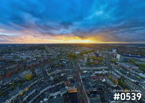 Luchtfoto van Keizer Karel Plein in Nijmegen met donkerblauwe wolken en een oranje gloed aan de horizon boven herfstbomen
