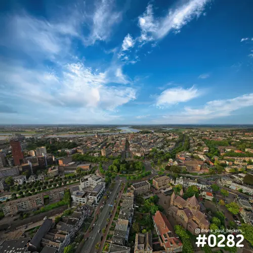 Luchtfoto van Keizer Karel Plein in Nijmegen met blauwe lucht en wolkenslierten boven de stad, rivier aan de horizon