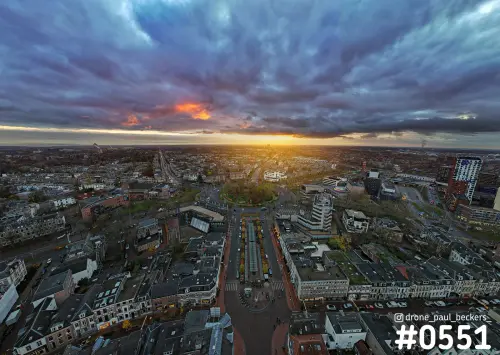 Luchtfoto van Keizer Karel Plein en het stationsgebied in Nijmegen bij zonsondergang, met donkere wolken en oranje gloed