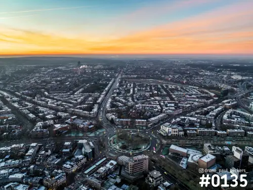 Luchtfoto van het Keizer Karel Plein in Nijmegen bij zonsopkomst, met oranje lucht boven de woonwijken en de lange laan