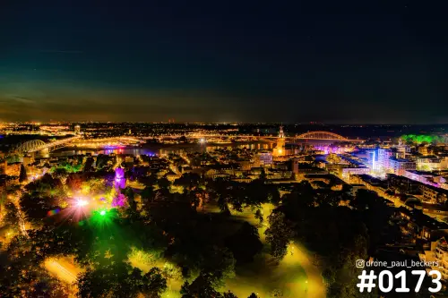 Luchtfoto van Nijmegen bij nacht: gekleurde lichten in het Kronenburgerpark, verlichte Stevenskerk en bruggen over de Waal