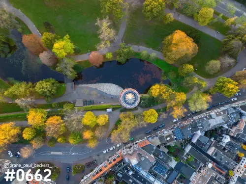 Luchtfoto van het Kronenburgerpark in Nijmegen in de herfst, met vijver en ronde glazen koepel tussen gele bomen