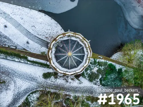 Luchtfoto van een veelhoekig paviljoen in het Kronenburgerpark in Nijmegen, met sneeuw en een deels bevroren vijver