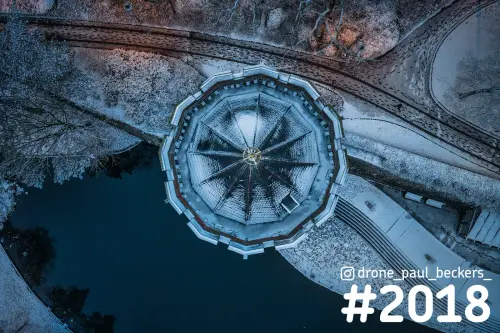 Luchtfoto van boven op een besneeuwd paviljoen naast de vijver in het Kronenburgerpark in Nijmegen, in blauw schemerlicht