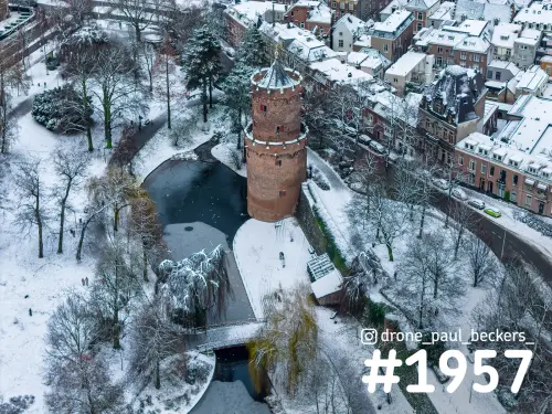 Luchtfoto van de bakstenen toren in het Kronenburgerpark in Nijmegen, met bevroren vijver en besneeuwde daken